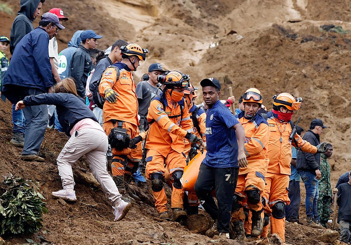 Integrantes de la Defensa Civil colombiana trasladan el cuerpo de una persona