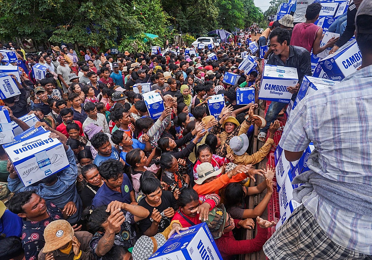 La gente hace cola para recibir suministros de agua donados en un campamento camboyano