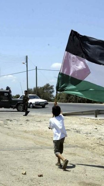 Un niño ondea una bandera palestina ante una patrulla israelí, en una imagen de archivo