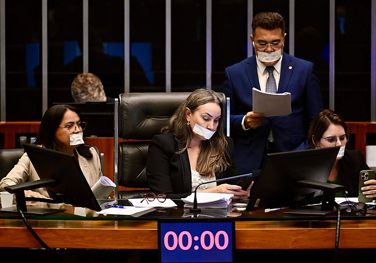 Legisladores de oposición, con la boca tapada con cinta adhesiva, ocupan el escritorio del presidente durante una sesión plenaria en protesta contra la orden de arresto domiciliario emitida contra Bolsonaro