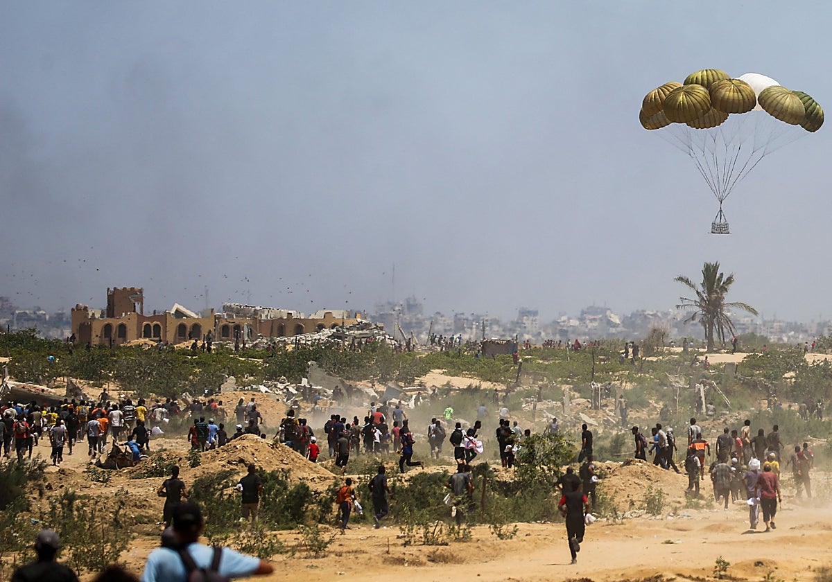 Palestinos se apresuran a recuperar paquetes de ayuda durante un lanzamiento aéreo sobre Nuseirat, en el centro de la Franja