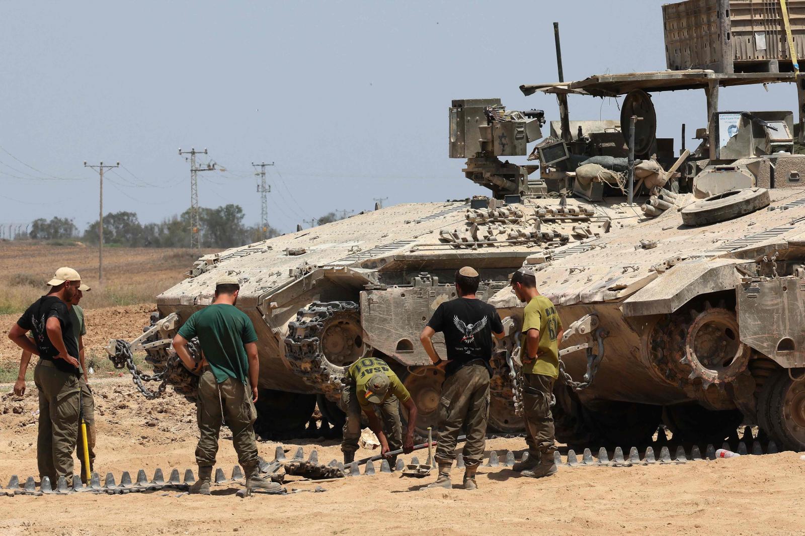 Soldados israelíes trabajando en la cadena de un tanque en la zona fronteriza del territorio palestino sitiado