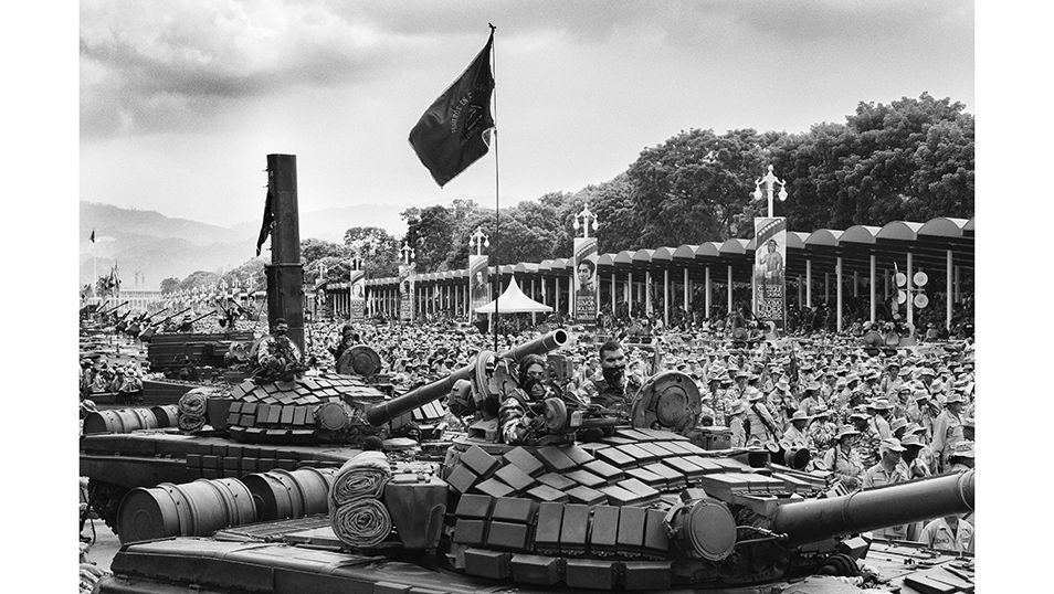 Tanques en formación mientras detrás, millas de milicianos uniformados llenan la avenida. La bandera ondea sobre los blindados, entre consignas y aplausos del público