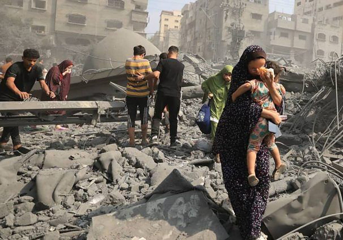 Mujer huye con su hija en brazos tras un bombardeo en Gaza