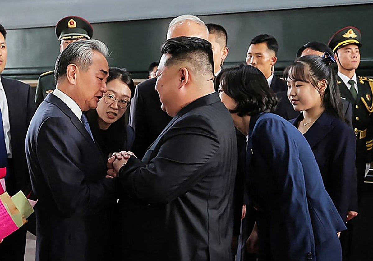 Kim Jong Un y su hija Kim Ju Ae (der.) son recibidos por el ministro de Asuntos Exteriores de China, Wang Yi, a su llegada a la estación de tren de Pekín