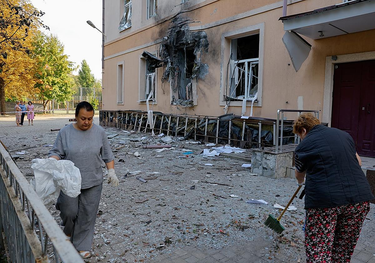 Mujeres retiran escombros del exterior de un edificio escolar dañado