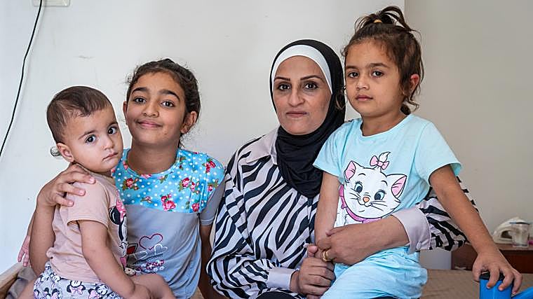 Rana, abogada en Gaza, sostiente a su hija MIra, herida en la guerra gravemente. También están sus otras dos hijas: Sara y Miriam