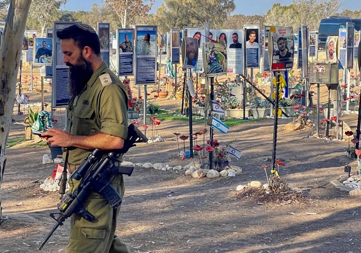 Fusil en ristre, un soldado israelí vigila el lugar del festival de música Nova, donde los terroristas mataron a 378 personas el 7-O