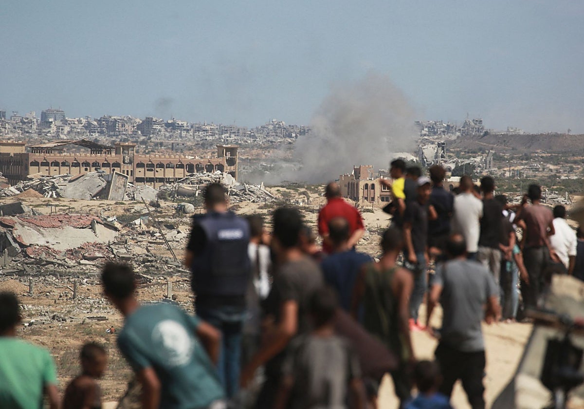 Palestinos observan columnas de humo tras bombardeos israelíes mientras se desplazan al sur desde Wadi Gaza