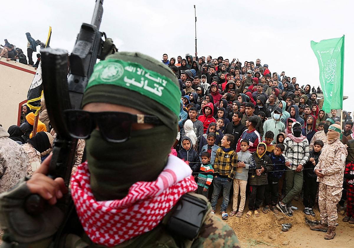 Un miliciano de Hamás, delante de un grupo de gazatíes