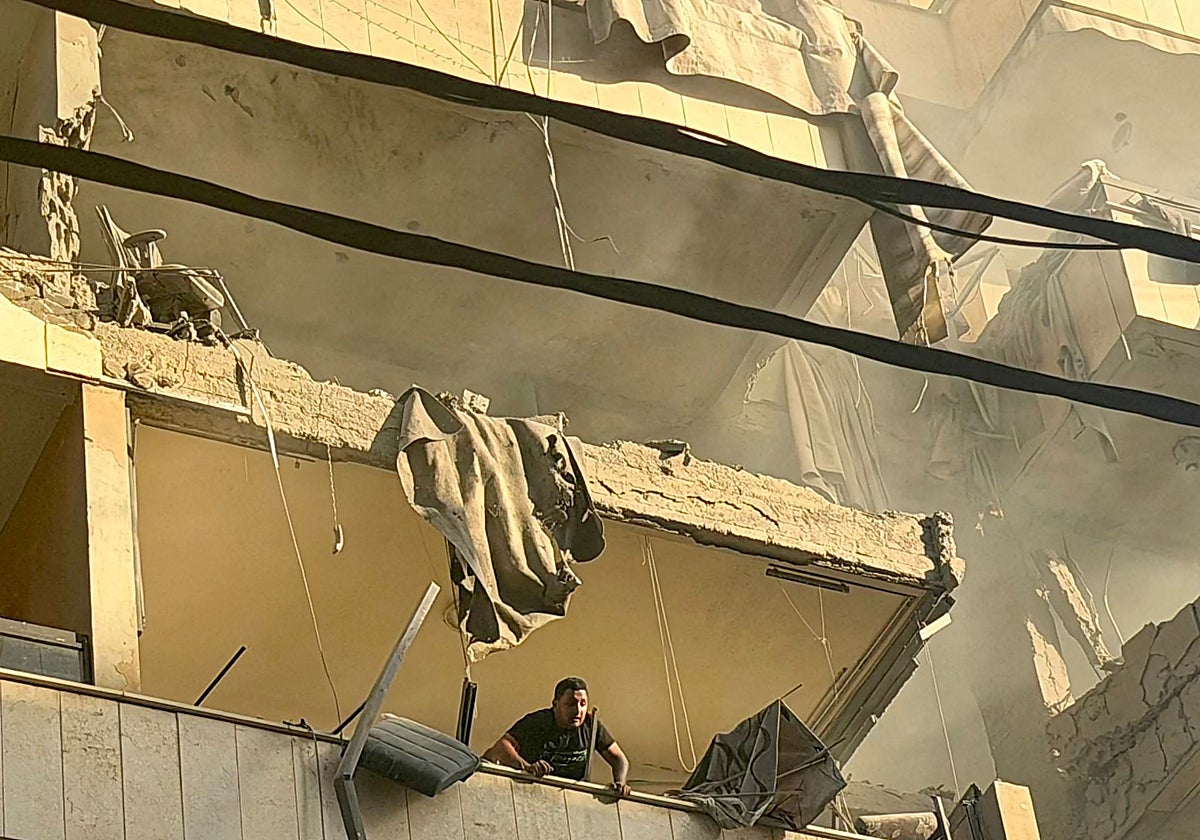 Un hombre mira desde un balcón después de un ataque militar israelí contra un edificio residencial en el barrio de Haret Hreik, en Beirut