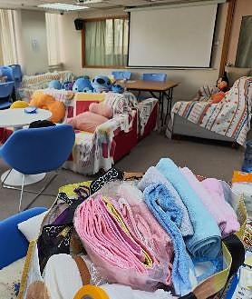 Imagen secundaria 2 - En la primera imagen, el pastor Chak Ming Yau junto a su hijo, con las donaciones almacenadas en las oficinas de su iglesia; en la segunda, andamios de bambú en el centro de Hong Kong; en la última un espacio de las oficinas de la iglesia reconvertido en refugio para las víctimas del incendio
