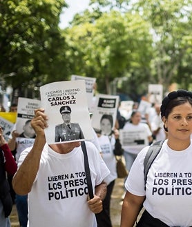 Imagem Secundária 2. A primeira imagem mostra o ex-General Raoul Baduel com seu filho Hosnars. No segundo e terceiro episódios, familiares e amigos de presos políticos protestam em Caracas, exigindo a libertação dos presos de consciência.