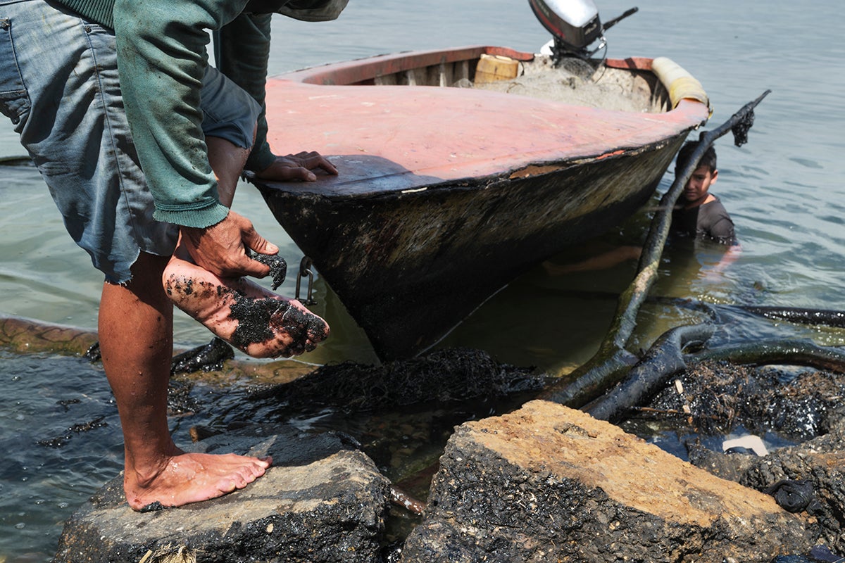(Primera foto) Alirio y su hijo empujan su bote hasta la orilla del lago tras un día de pesca. (Segunda) Jhon Luis Medina Lope llega a la orilla del Lago de Maracaibo tras un largo día de pesca de cangrejos. (Tercera) El petróleo se adhiere a la piel de los pescadores por los continuos derrames de petróleo y productos químicos e nla zona