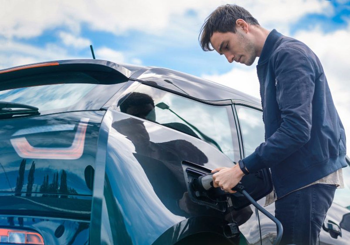 Un hombre recarga su coche eléctrico.