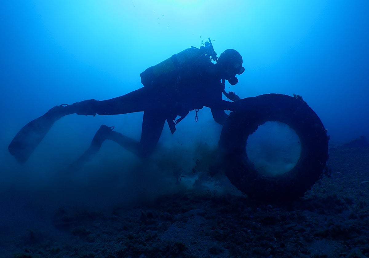 Uno de los buzos recoge un neumático del fondo del mar