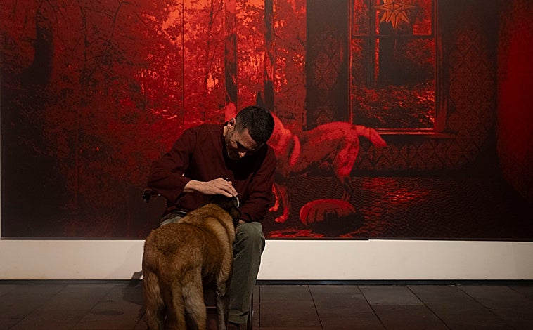 Imagen principal - Arriba, el pintor acaricia a su perro Metta, protagonista de su políptico. Sobre estas líneas, Garcerá frente a su inmensa biblioteca. A la derecha, explicando la pieza