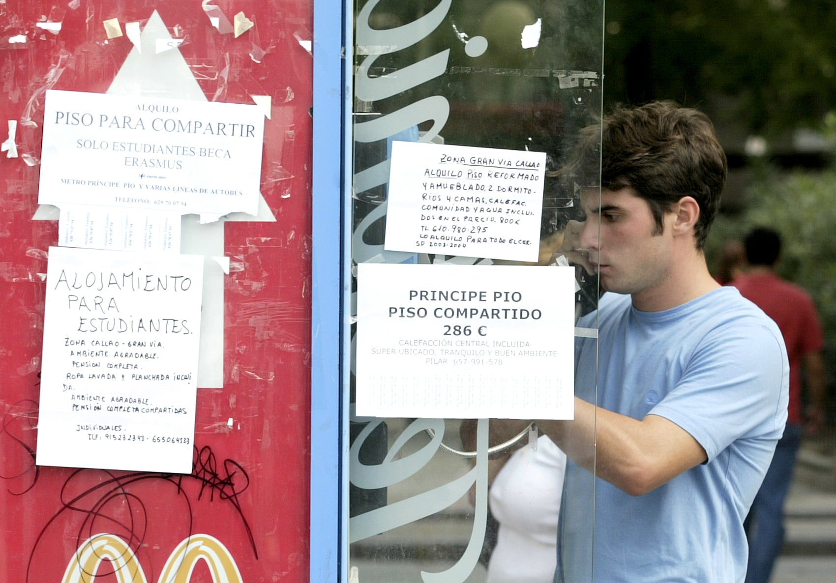 Joven colocando un cartel en el que busca compañero de piso