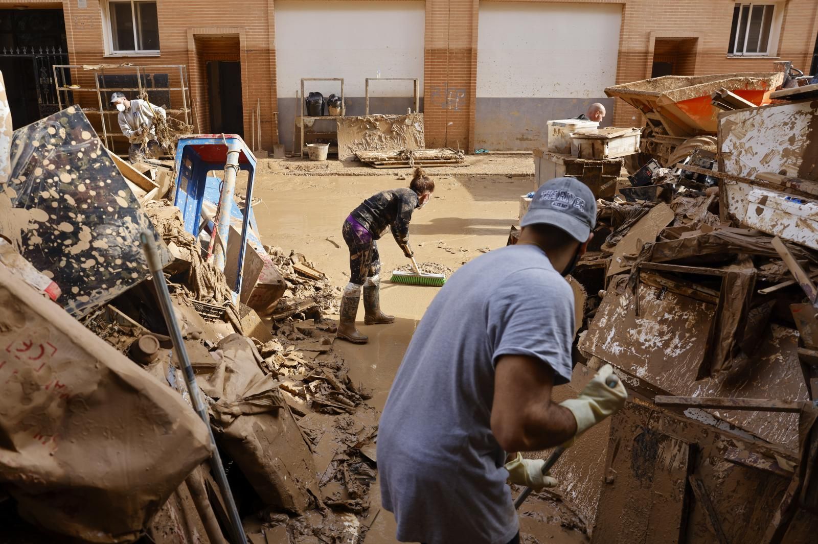 Dos personas limpian las calles afectadas por la DANA en Valencia