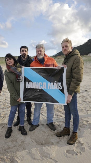 La candidata de Podemos a la Xunta, Isabel Faraldo (3i), posa con carteles de Nunca Máis en la playa de Traba