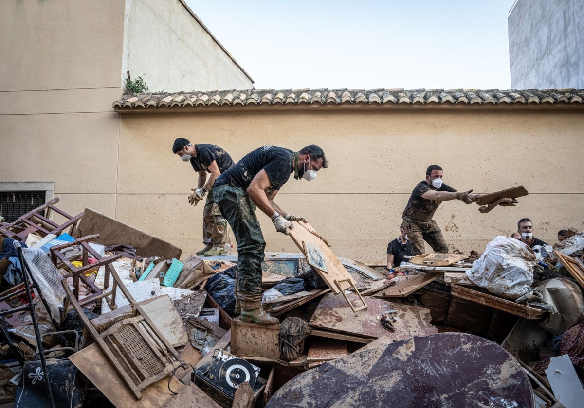 Un grupo de voluntarios ayuda a limpiar una de las calles de Catarroja afectadas por la DANA