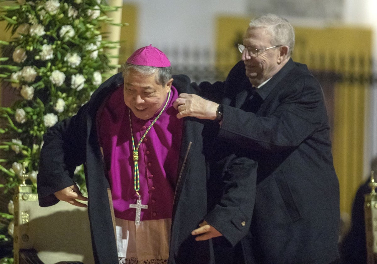 El presidente del Consejo colocándole el abrigo de Eduardo Carrera al nuncio apostólico Bernardito Auza