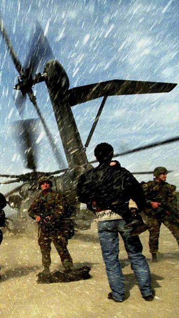 Un reportero bajo un helicóptero de guerra