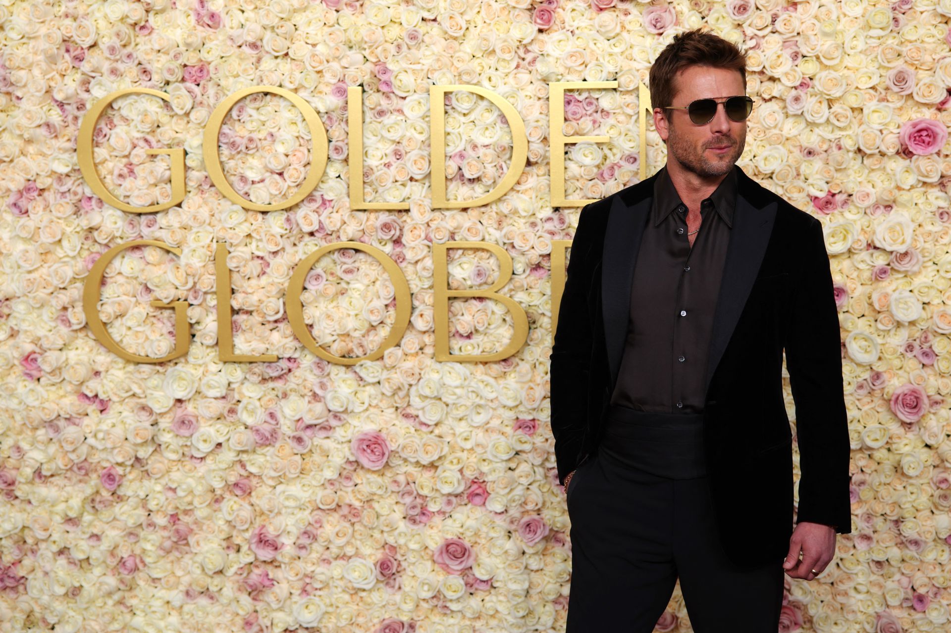 El actor Glen Powell, ataviado con unas gafas de sol en la alfombra roja de los premios.