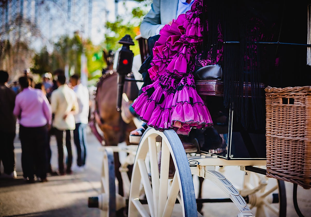Fotografía de una mujer vestida de flamenca en un coche de caballos