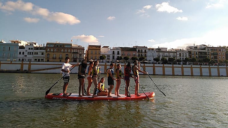 Un grupo de jóvenes practica paddle surf en el río Guadalquivir