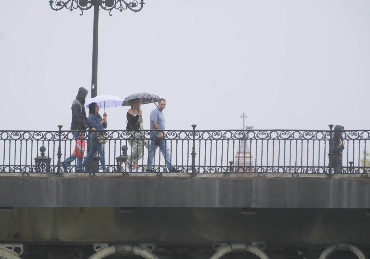 Transeúntes por el puente de Triana en esta lluviosa semana