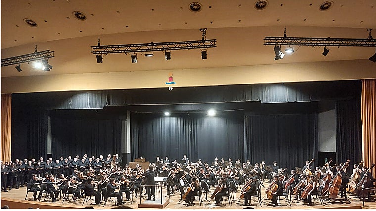 El coro masculina de la AA del Teatro de la Maestranza (izquierda), Juan García Rodríguez (director, en el centro) y la OSC
