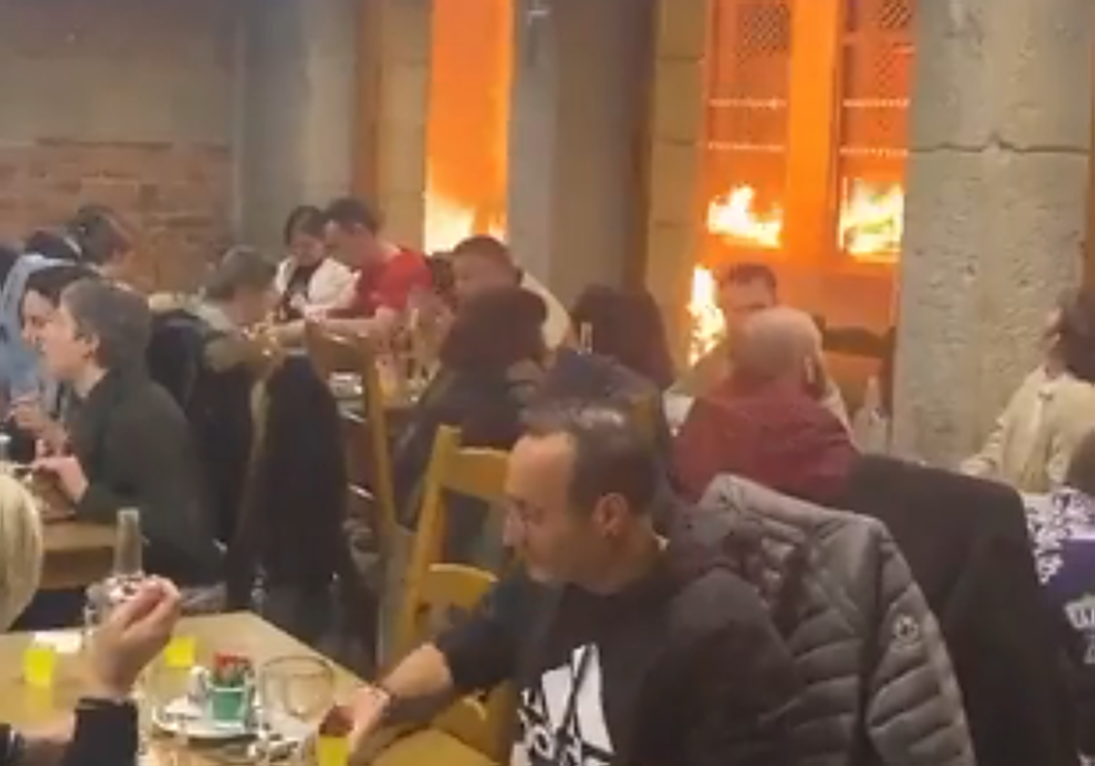 Vista desde el interior de un restaurante de Lyon, donde la gente cena indiferente a las llamas