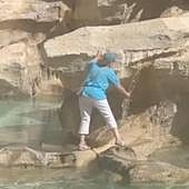 Una turista se sube a la Fontana di Trevi para llenar su botella de agua