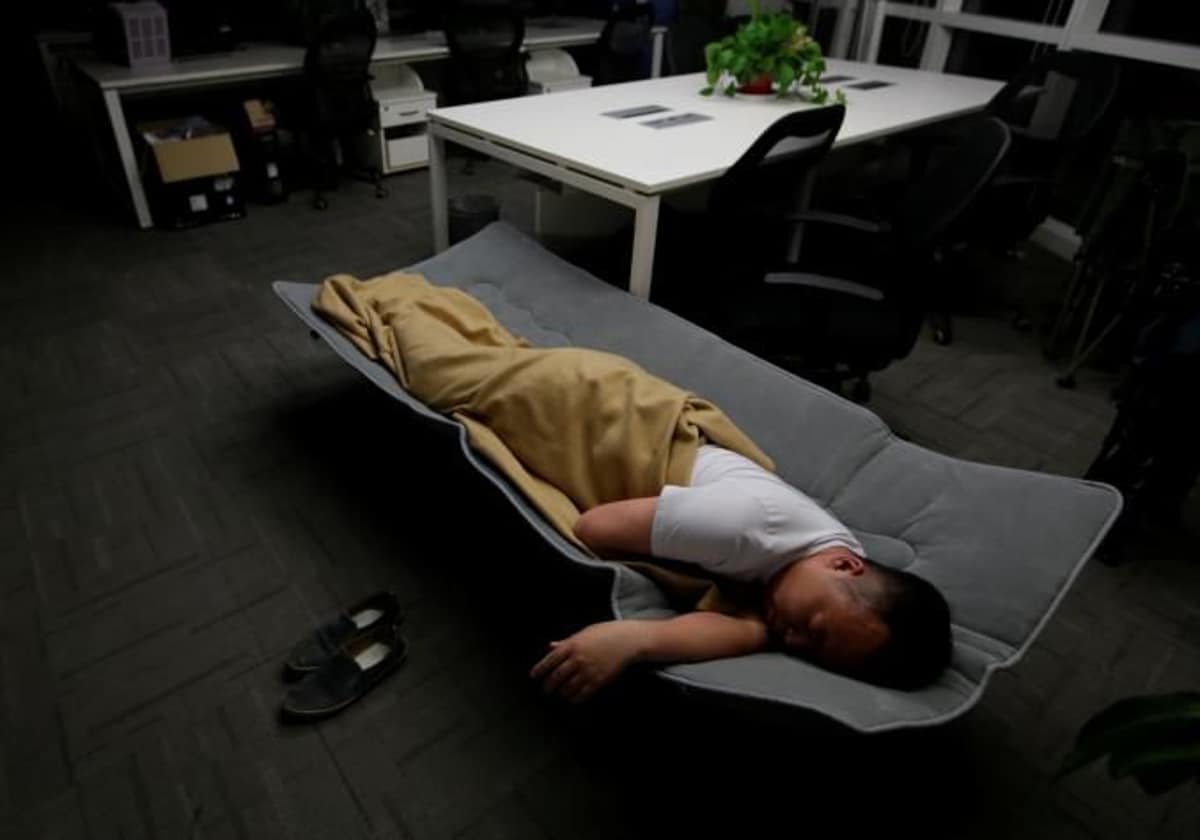 Un hombre durmiendo en una cama plegable en la oficina, en una imagen de archivo