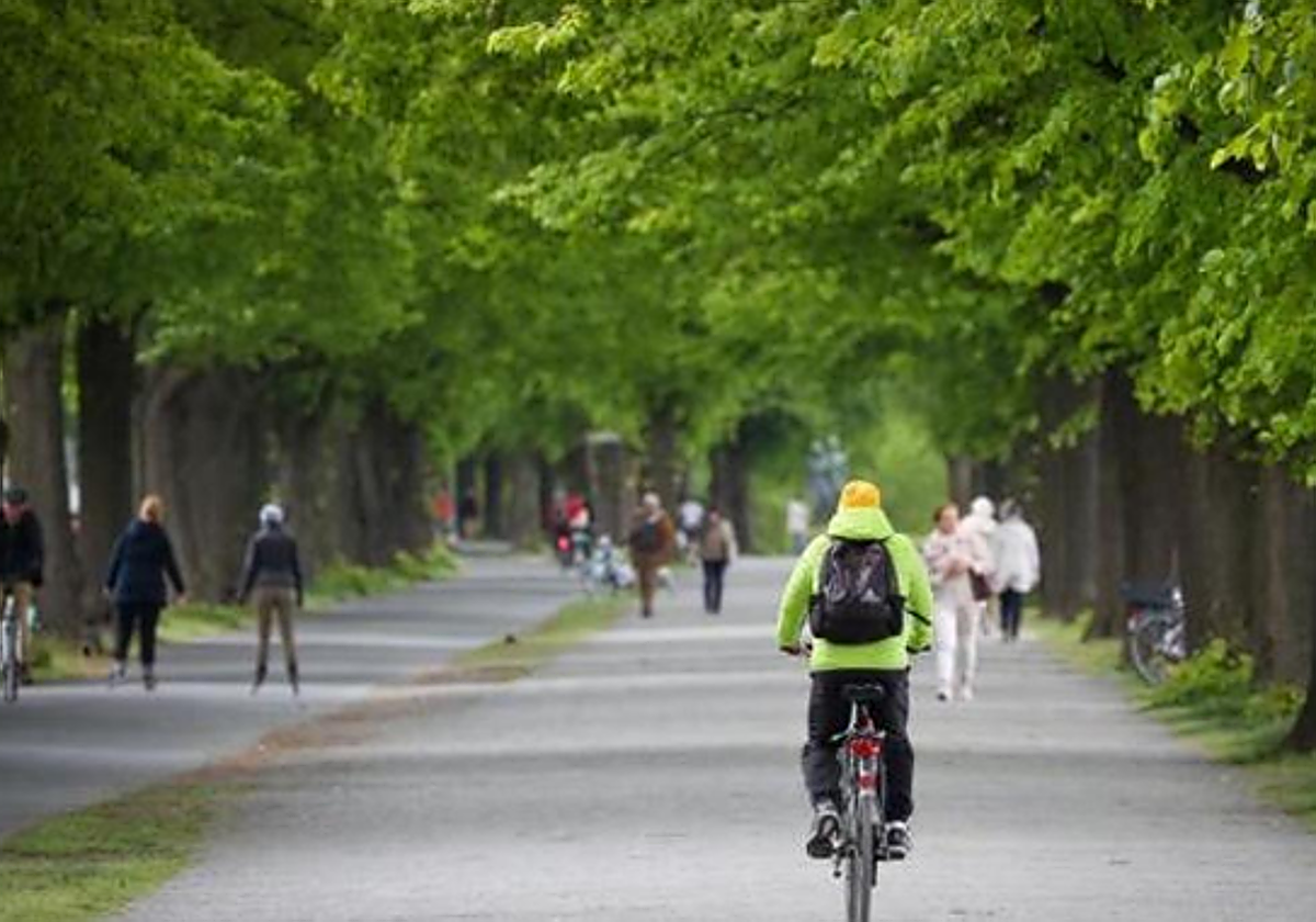Un grupo de ciclistas y viandantes pasean por un parque en Hannover (Alemania)