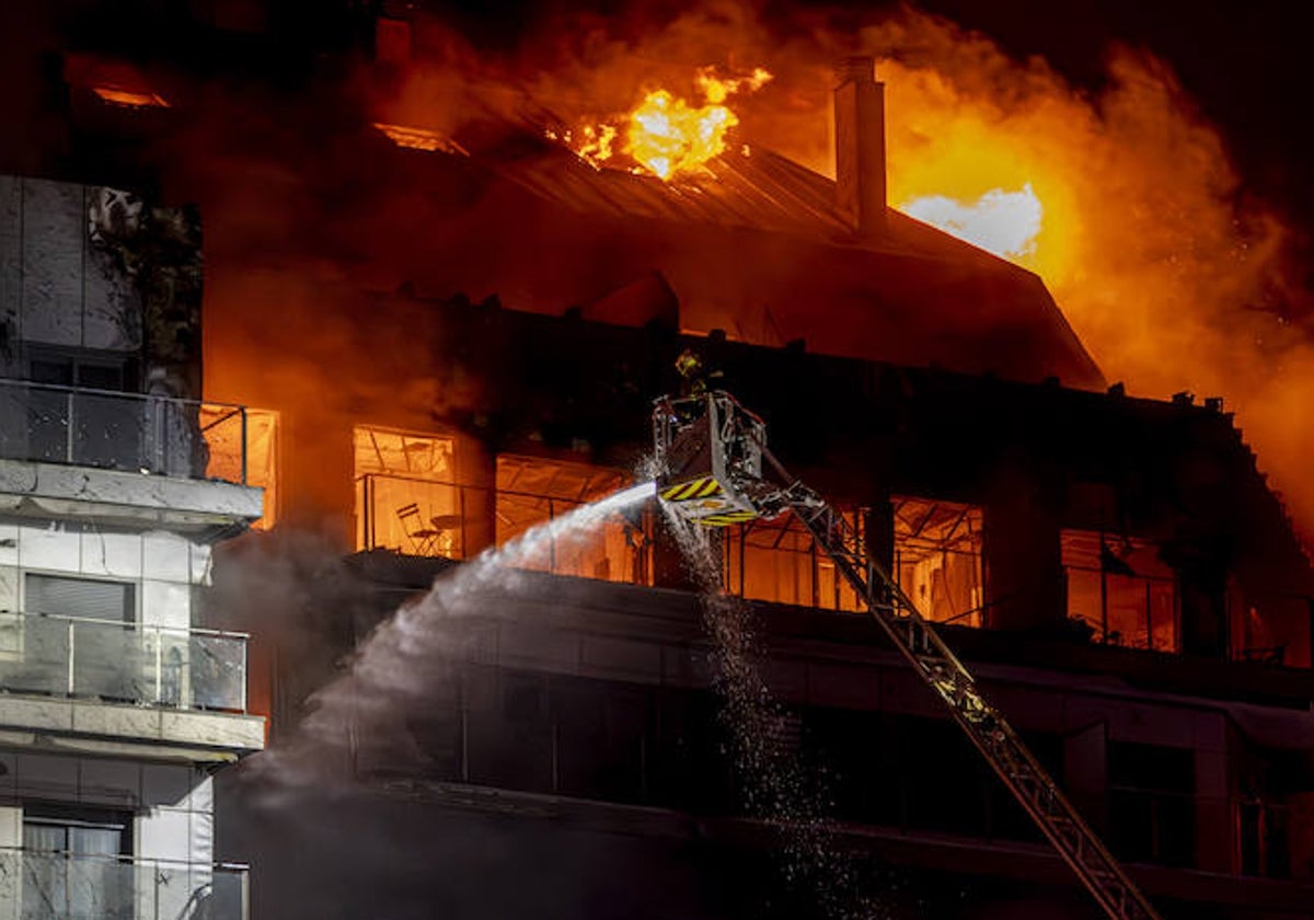 Bomberos trabajan en el incendio declarado sobre las cinco y media de la tarde del jueves en un quinto piso de un edificio de viviendas de Valencia que ha afectado totalmente al inmueble y se ha propagado a otro anexo