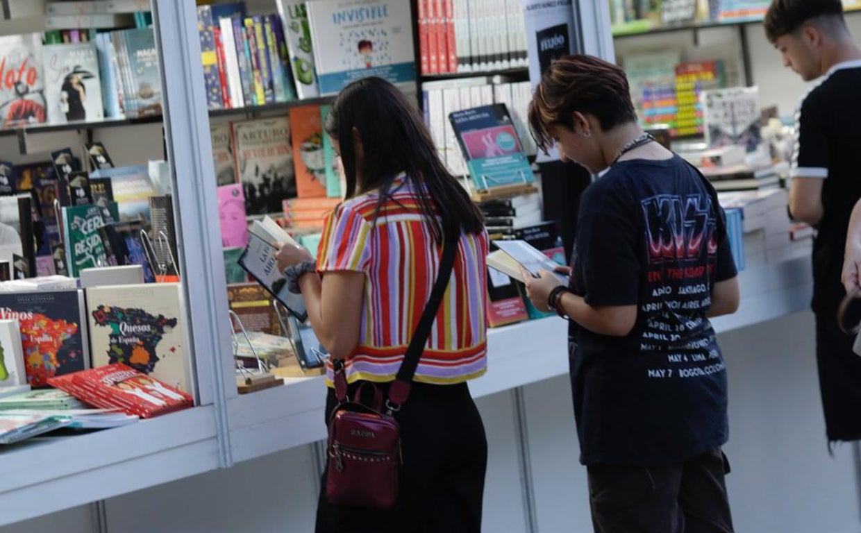 Dos visitantes hojeando libros de una caseta en la inuauguración de la Feria del Libro de Sevilla