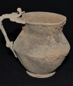 Imagen secundaria 2 - En la imagen de arriba, restos óseos y joyas hallados en la tumba de la excavación de La Puebla de Cazalla. A la izquierda sobre estas líneas, restos de lo que en su época era considerado como un pintalabios y a la derecha, una jarra que formaba parte del ajuar