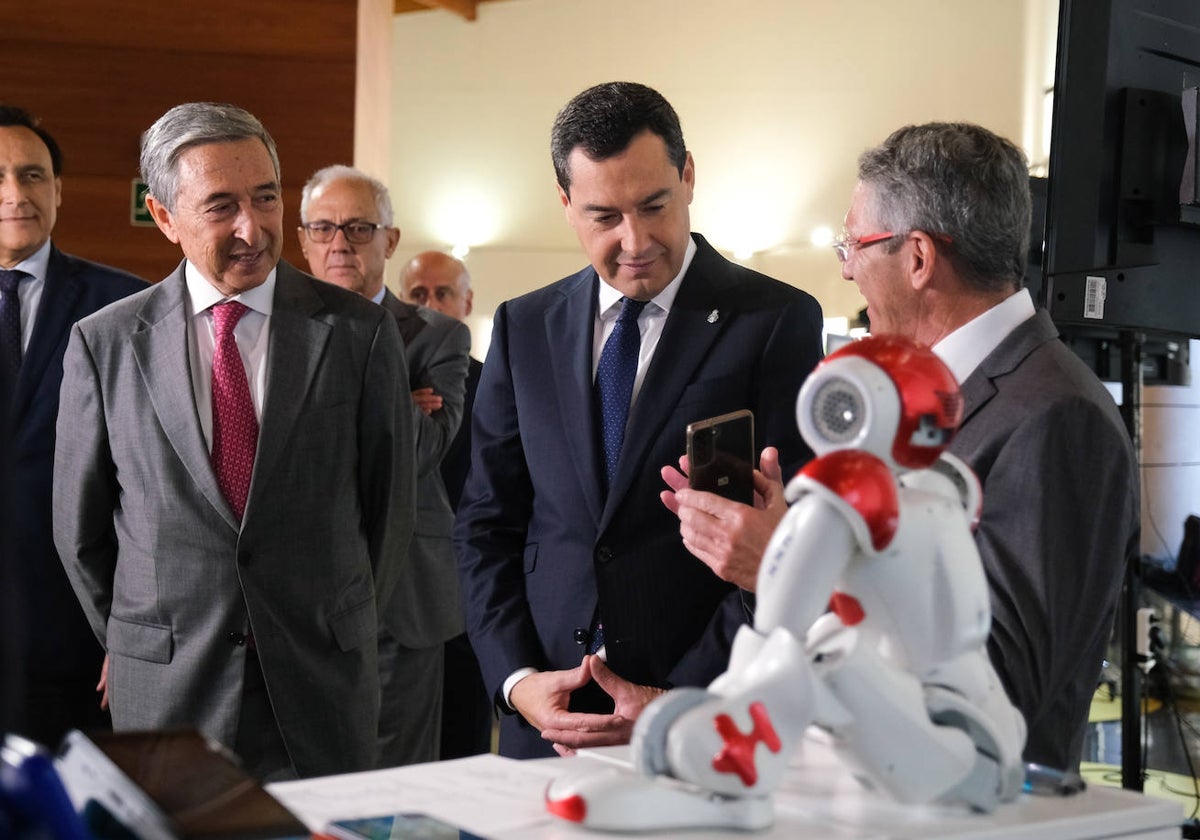 Francisco Mochón y Juanma Moreno escuchan las explicaciones de un directivo durante la visita a la exposición de proyectos de empresas innovadoras