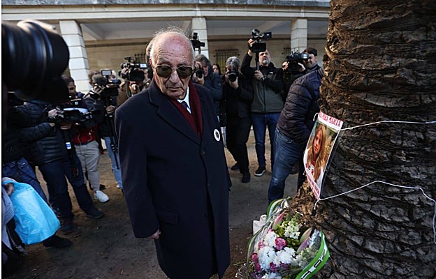 El abuelo de Marta junto a la foto de su nieta y el ramo de flores depositado en los juzgados de Sevilla