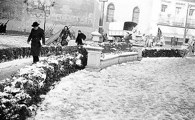 Sevillanos caminando entre la nieve por la plaza de la Encarnación