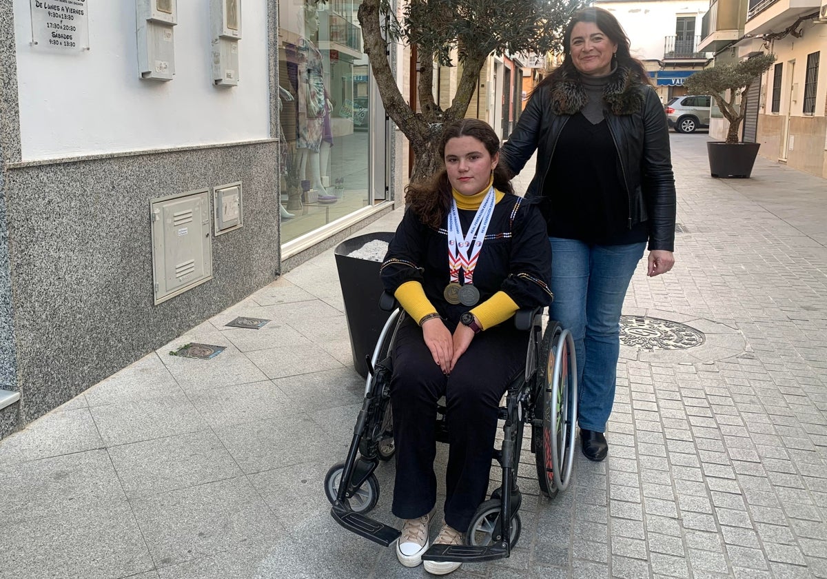 Silvia Romero con su hija Carlota, en silla de ruedas y con sus medallas deportivas