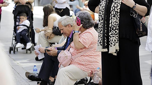 Una familia esperando en una calle del Centro a una cofradía