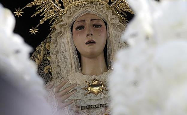El rostro de la Virgen de los Dolores entre las velas rizadas de la candelería