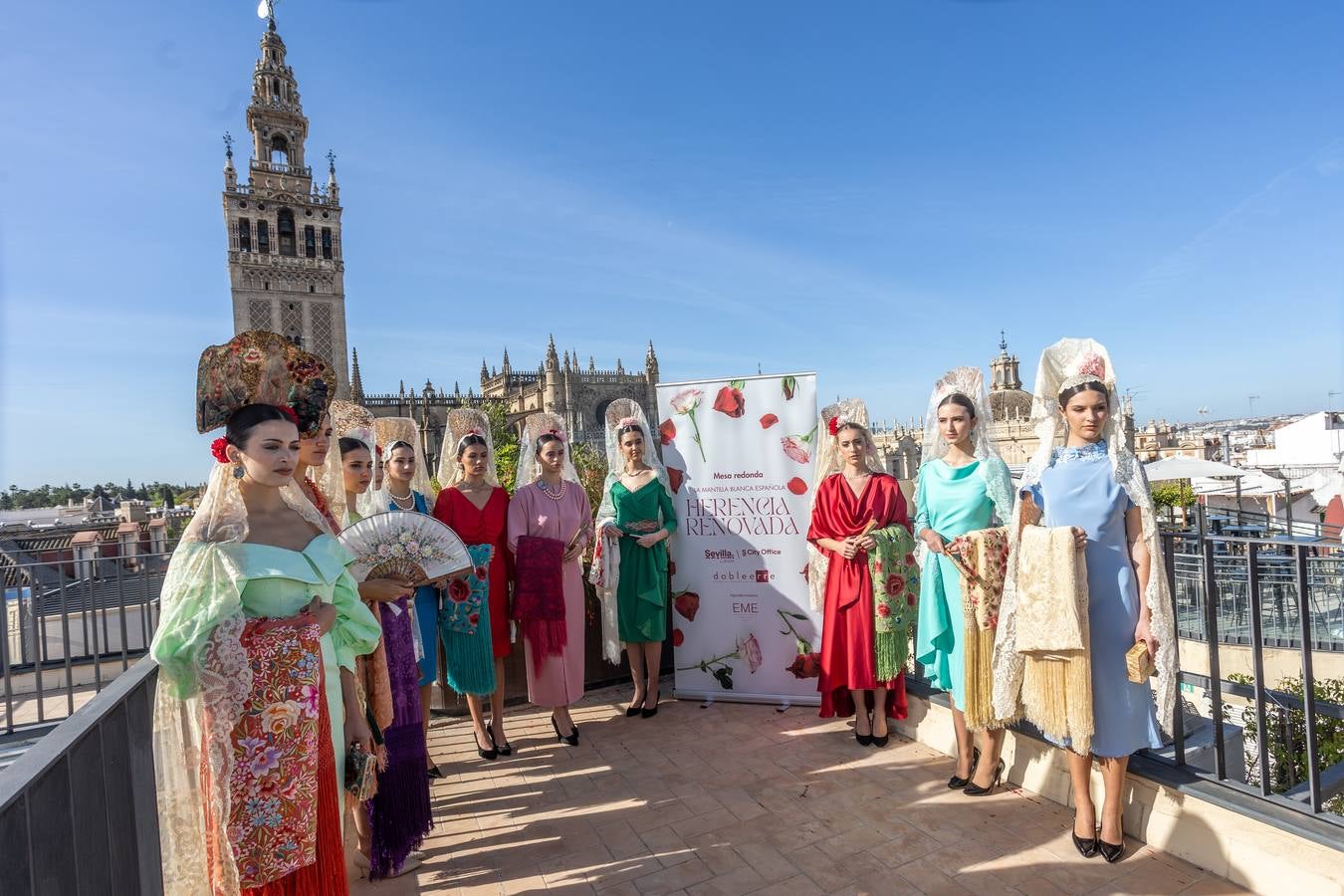 Unas jóvenes con mantilla blanca posan con la Giralda al fondo en la jornada de la Mantilla blanca