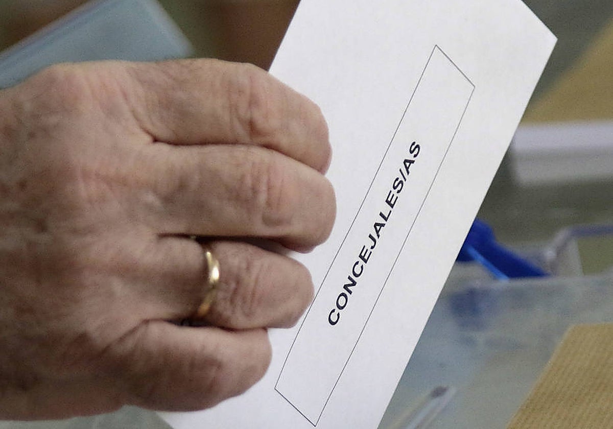 Una persona introduce un sobre electoral con su voto en unas elecciones municipales