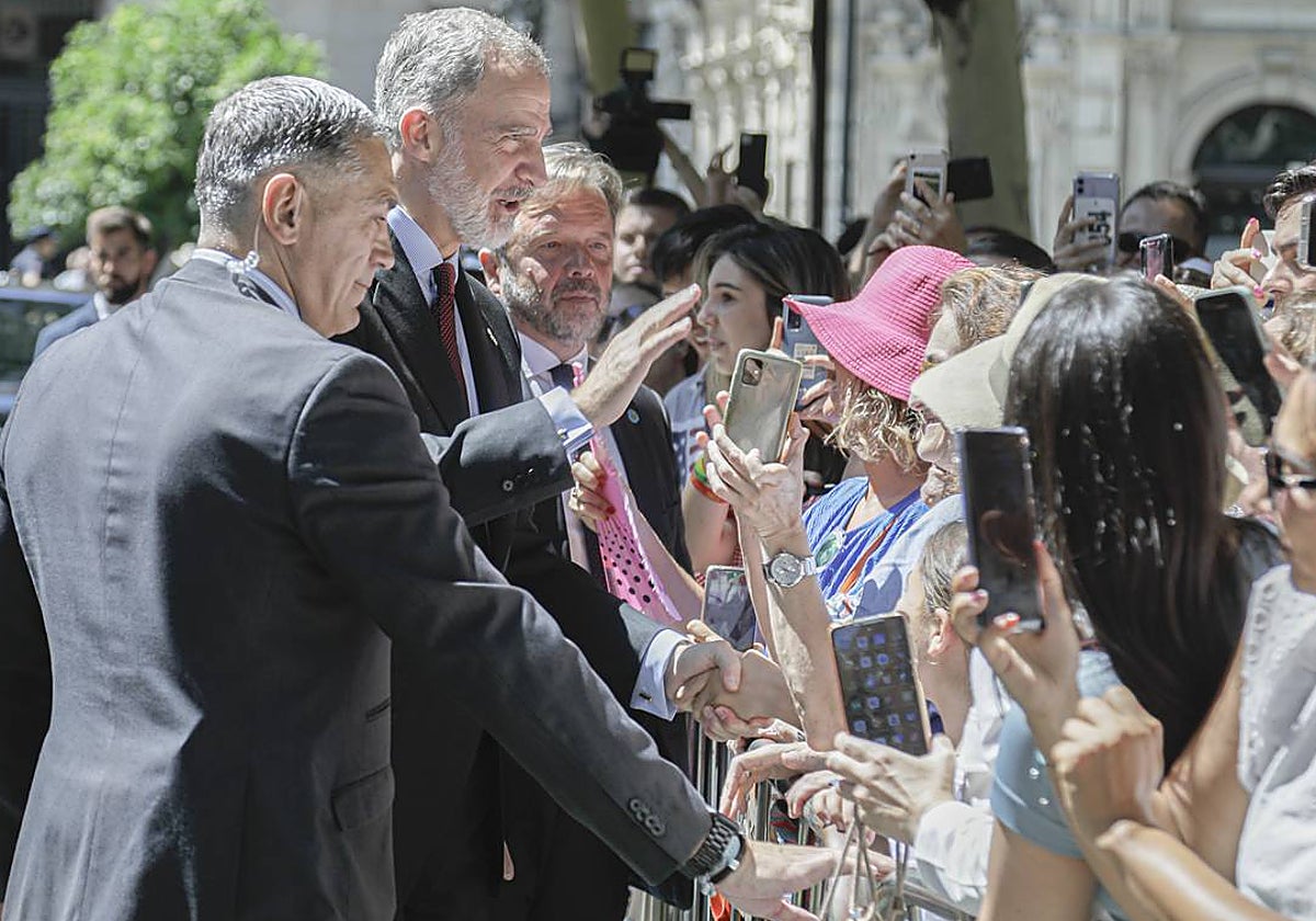 El Rey Felipe VI saluda a algunas personas que se han congregado frente al Ayuntamiento de Sevilla para recibirlo