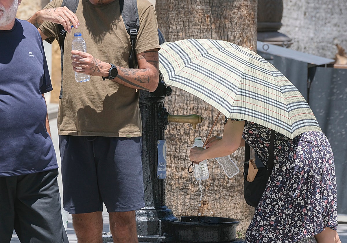 Mujer rellenado botella de agua con un parasol