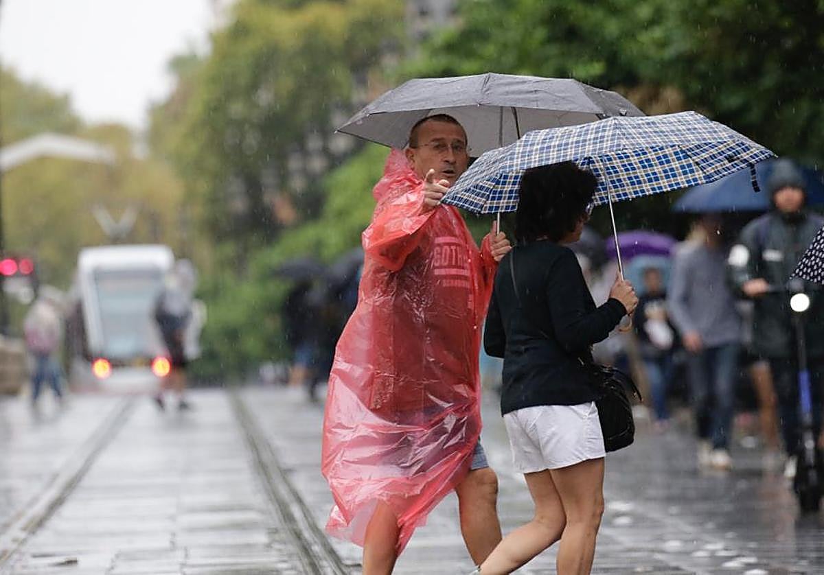 Dos personas caminan mientras cae la lluvia en el Centro de Sevilla